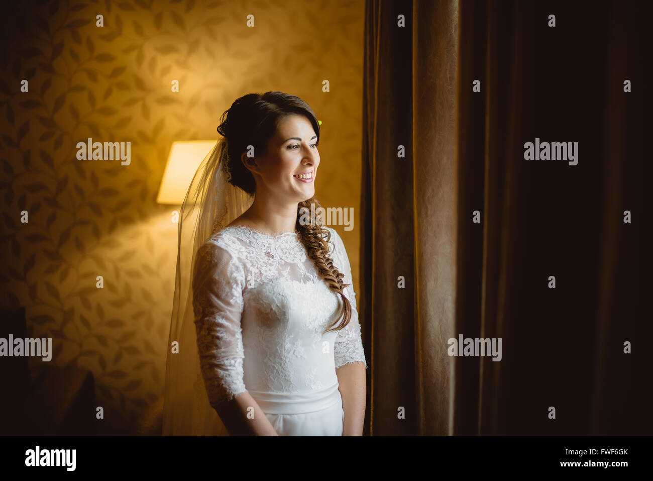 bride in a white dress standing near window Stock Photo - Alamy