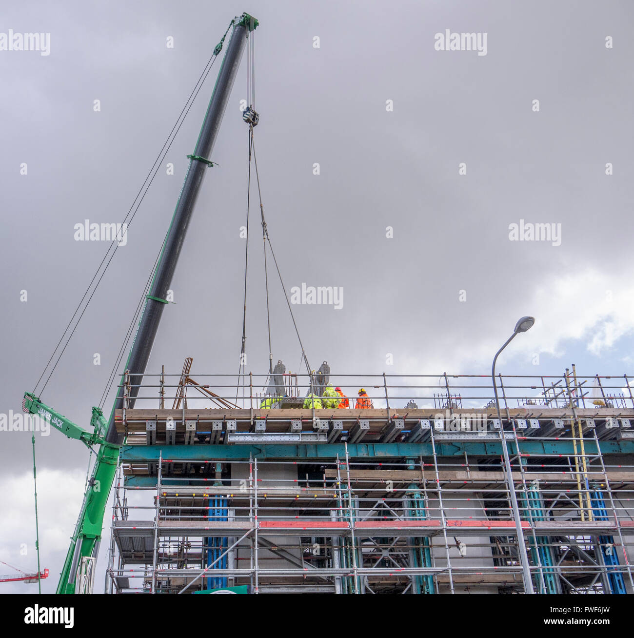 Construction workers fitting concrete pillars using a large crane Stock Photo
