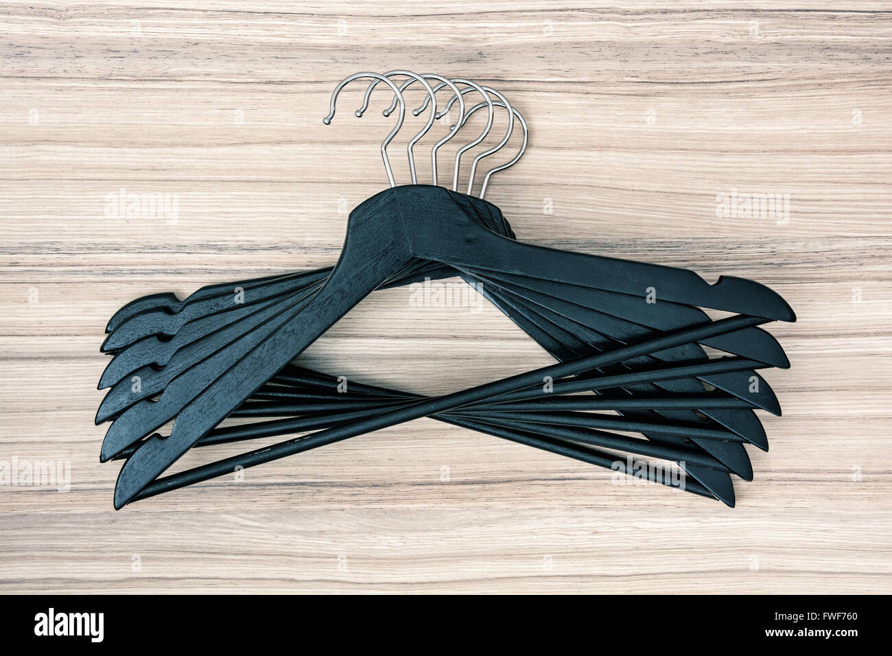 Set of black coat hangers on the wooden background. Stock Photo
