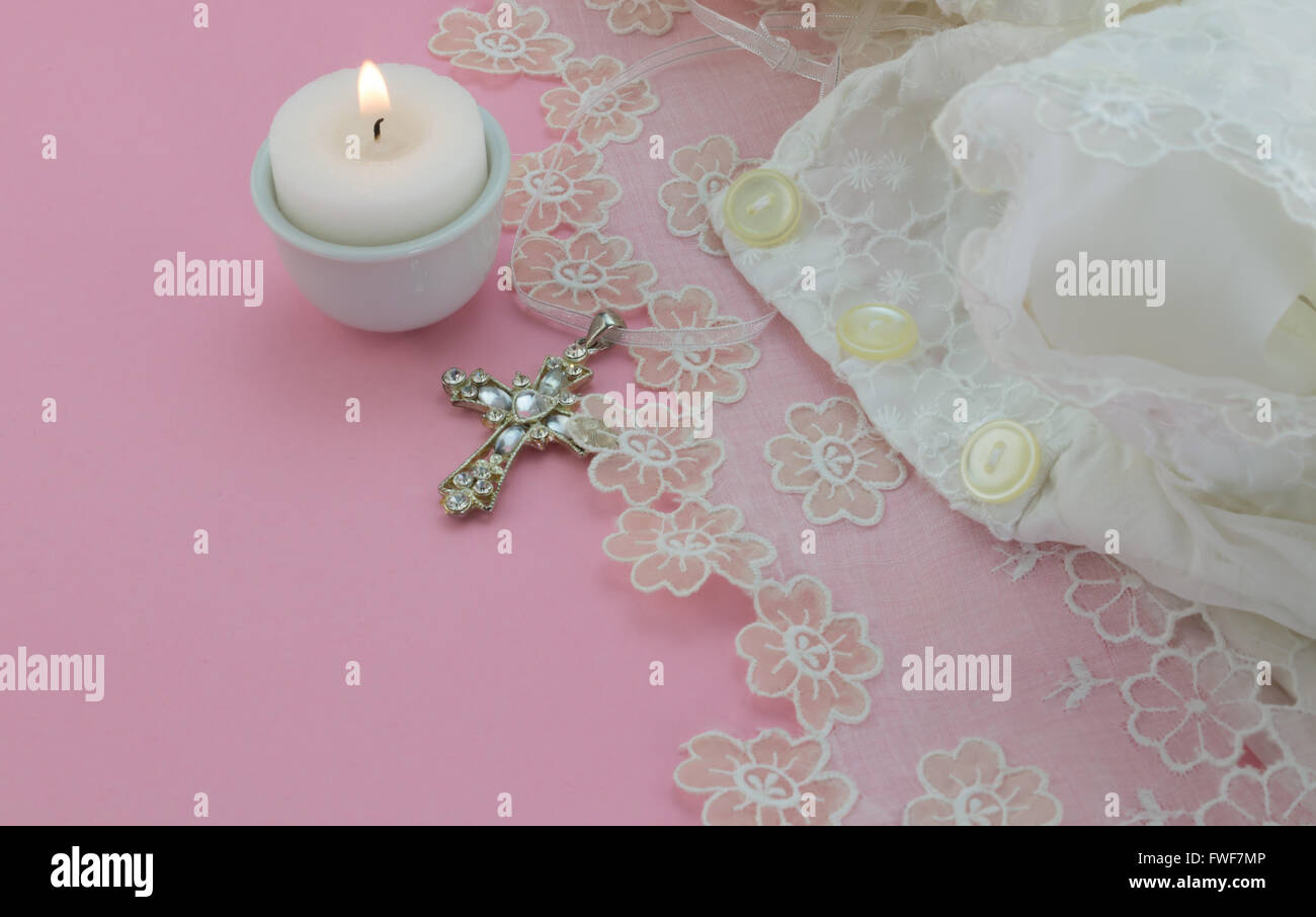Vintage baptism baby dress on pink background with cross and candle