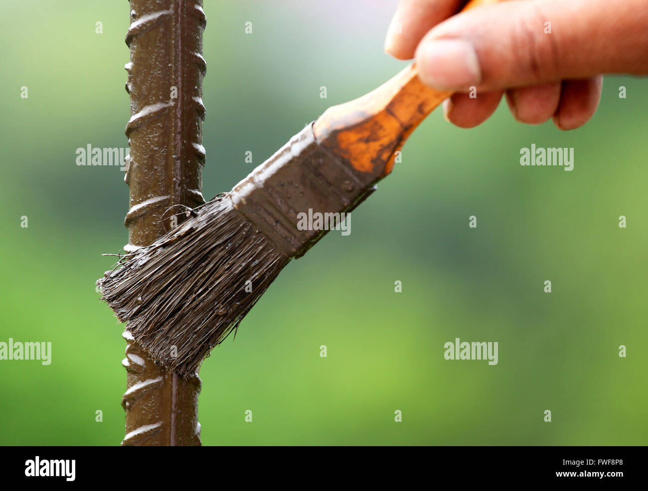 Painting an iron rod with a brush outdoor Stock Photo