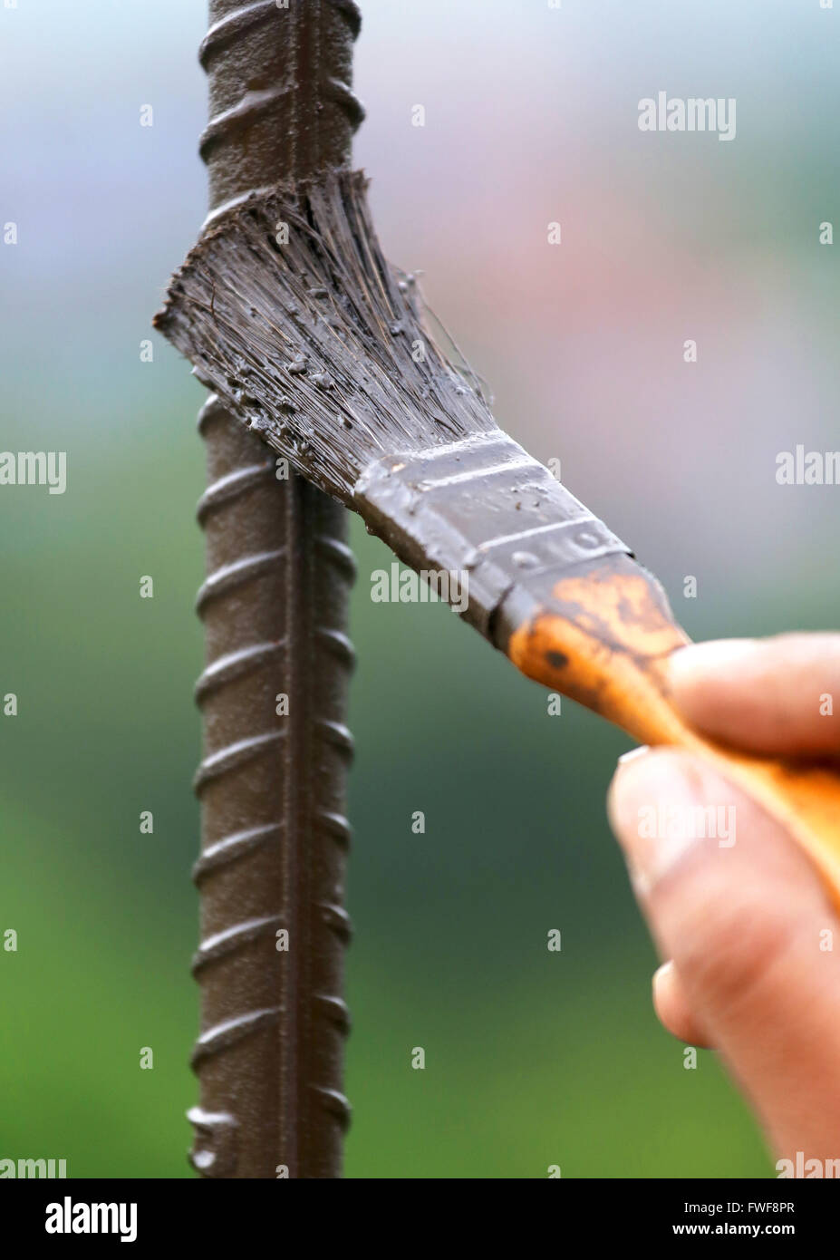 Painting an iron rod with a brush outdoor Stock Photo - Alamy