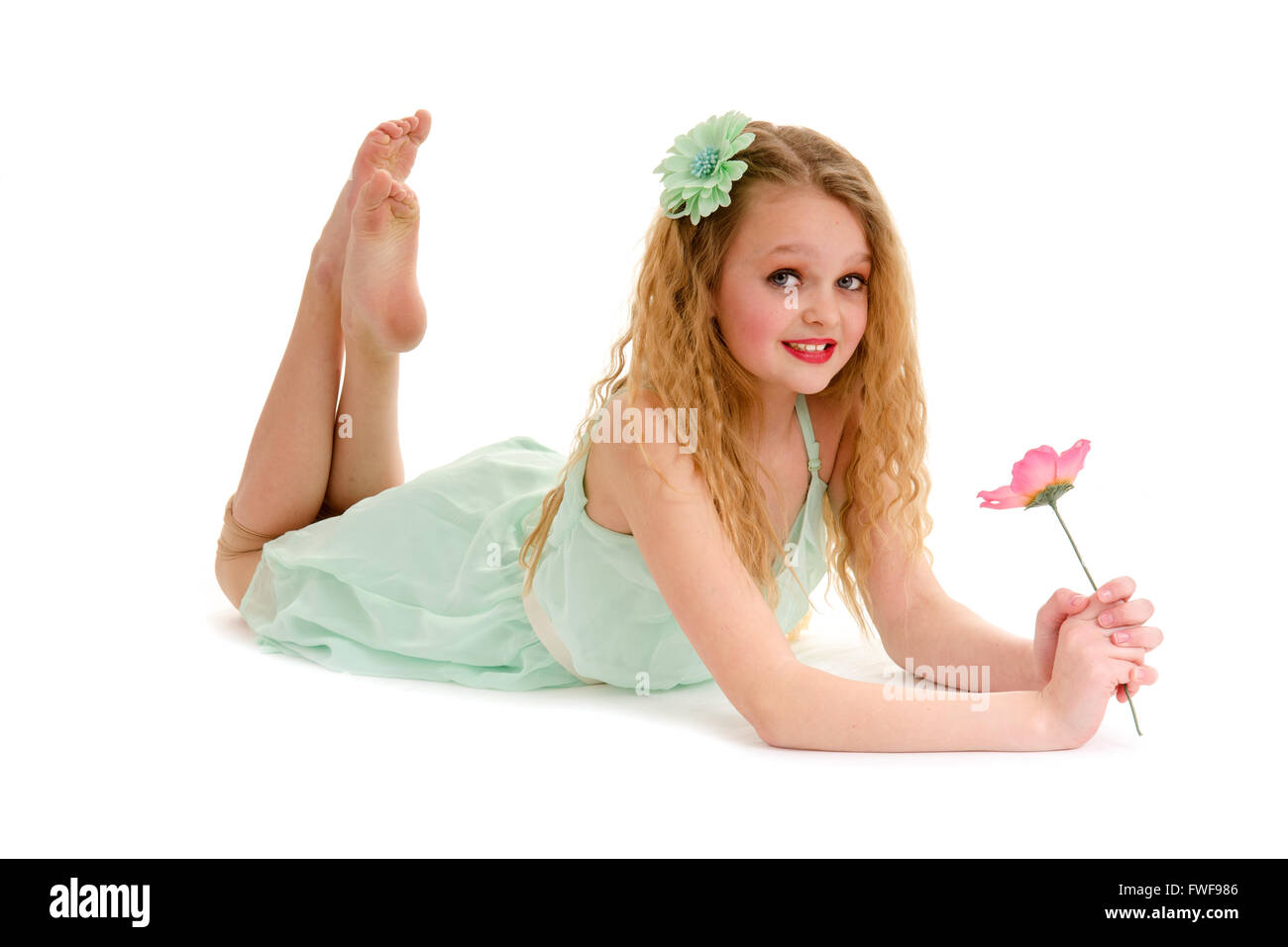 Preteen Blond Dancer Girl Holds a Flower Lying on Tummy on Floor Stock Photo
