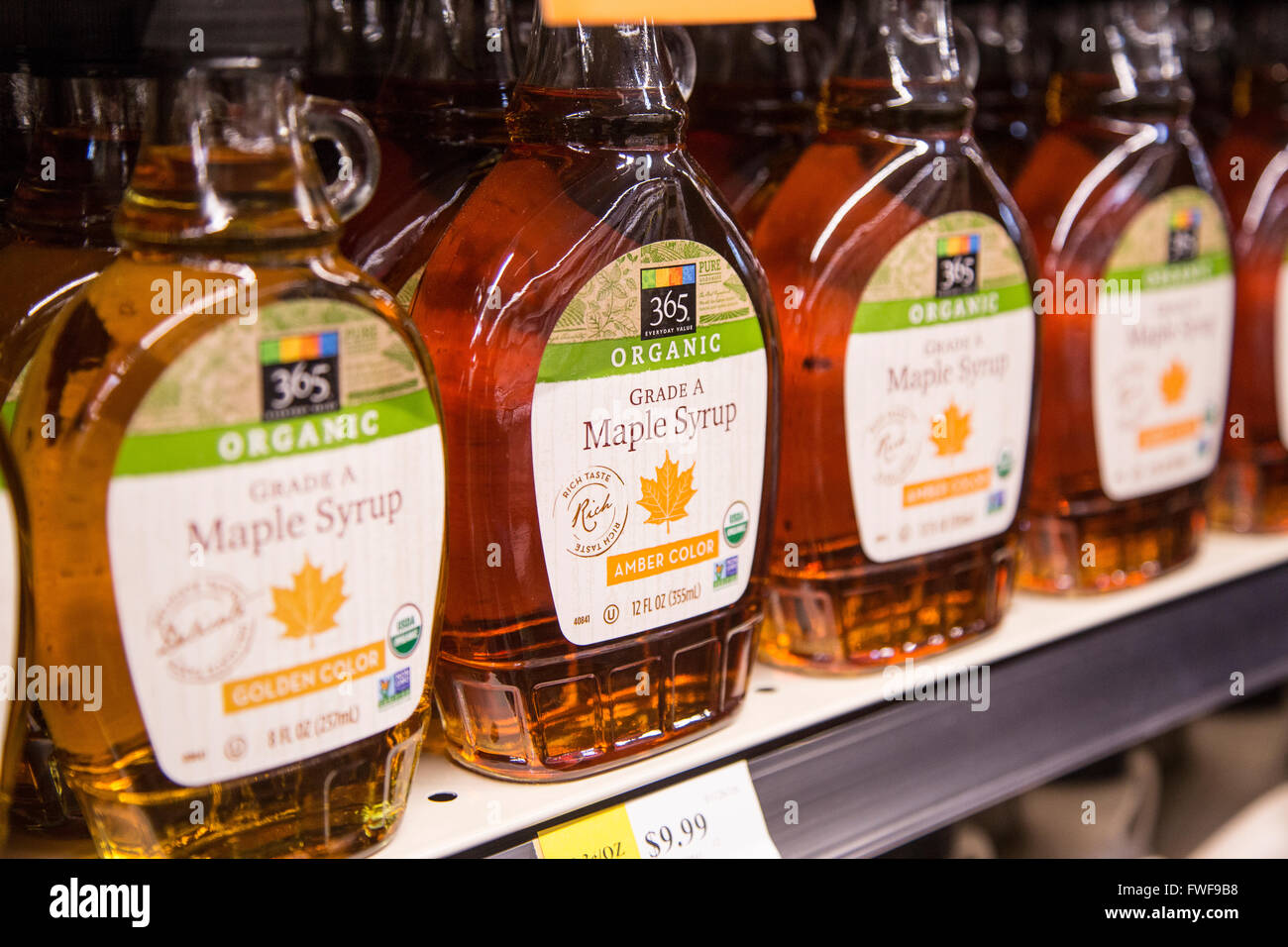 A shelf of organic maple syrup bottles on the shelf of a grocery store. Stock Photo