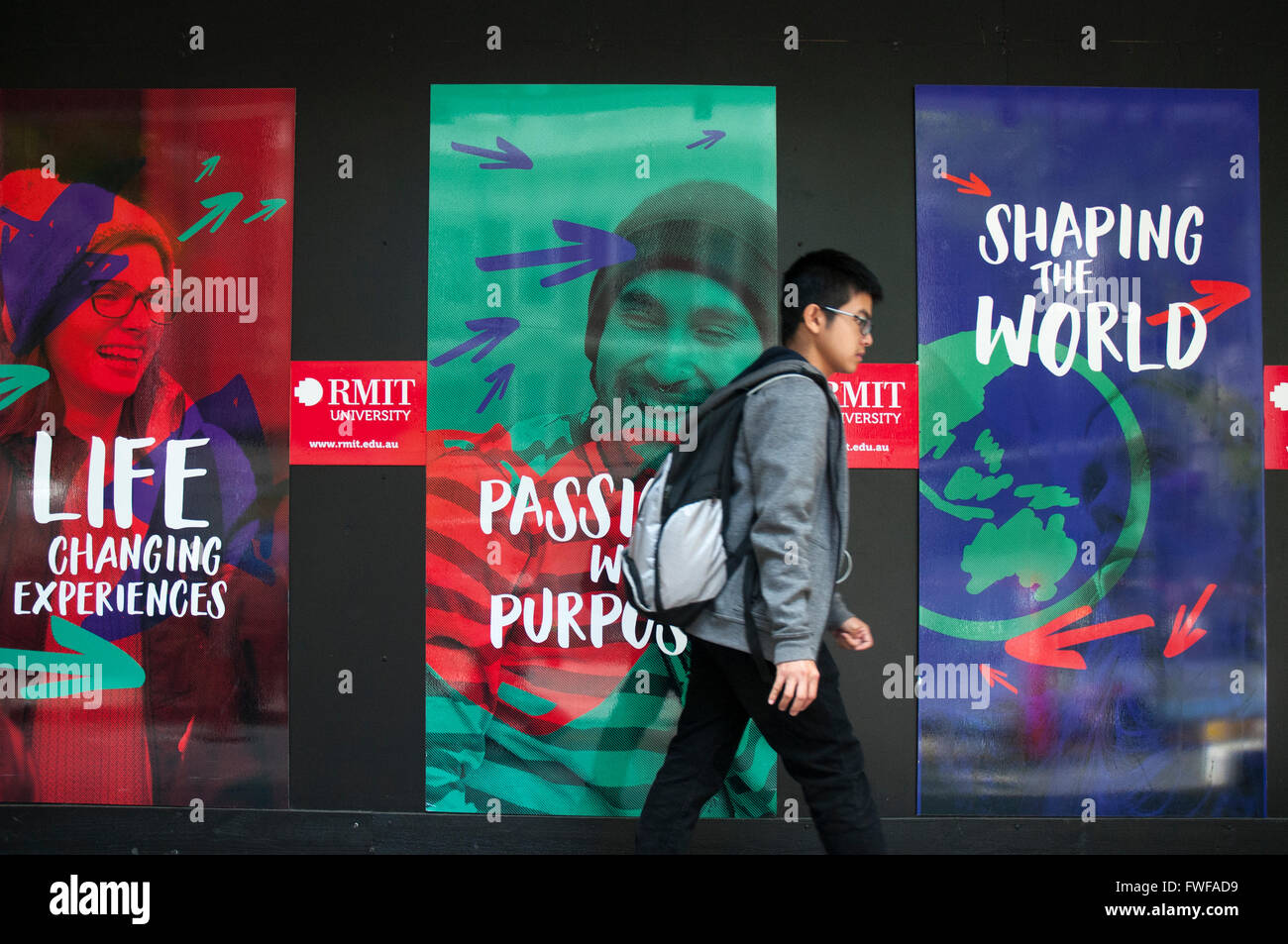 A student passing promotional banners outside the RMIT University buildings on Swanston Street, Melbourne Stock Photo