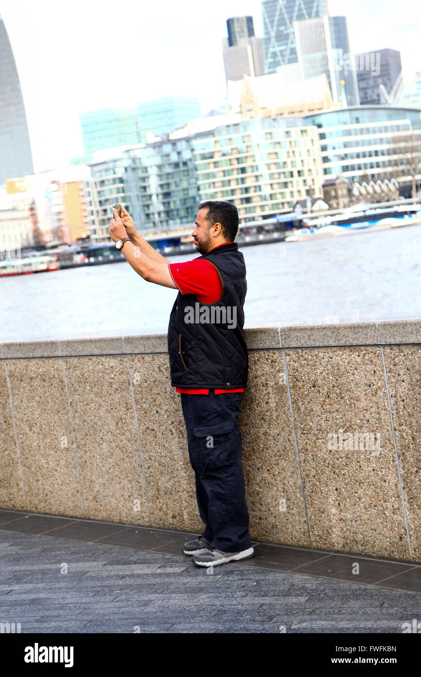 London - 5 April 2016 - Tourist takes a selfie with City Hall and Tower Bridge in the background on a sunny day in London Credit:  Dinendra Haria/Alamy Live News Stock Photo