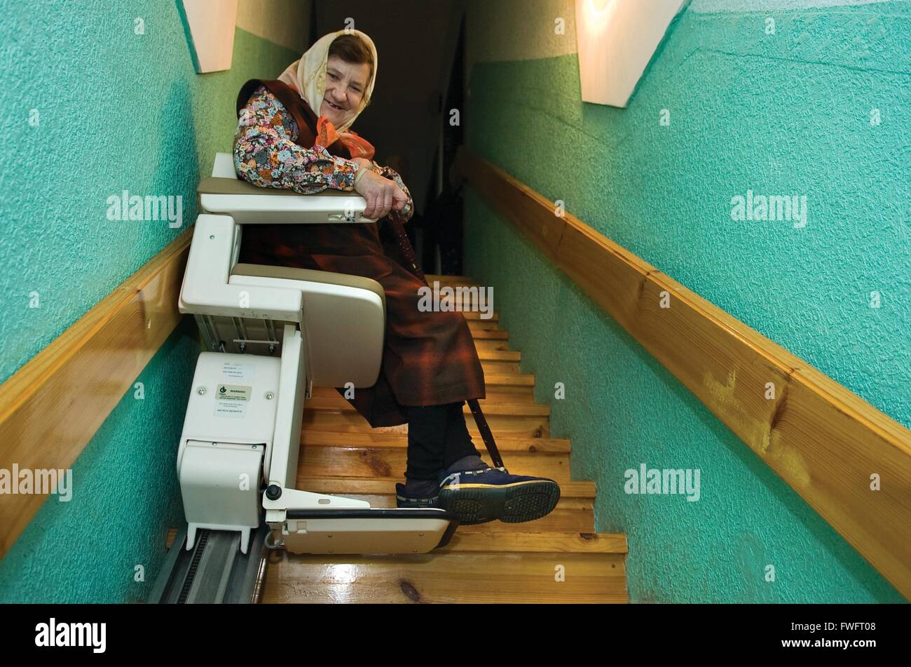 Chervona, Ukraine. An elderly woman sits smiling on a stair lift in the Home of Charity, a care home for elderly people supported by International Aid Trust, Much Hoole, Preston, Lancashire, UK Stock Photo