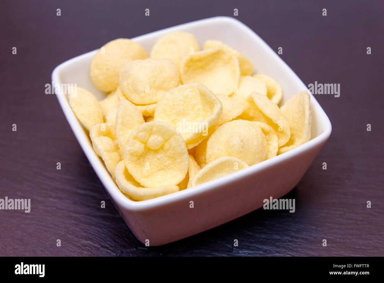 potato snacks on a square bowl on slate top Stock Photo