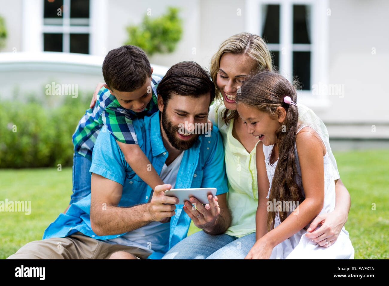 Happy family looking into mobile phone at yard Stock Photo Alamy