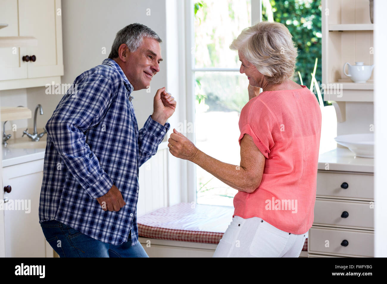 Playful senior couple dancing in kitchen Stock Photo