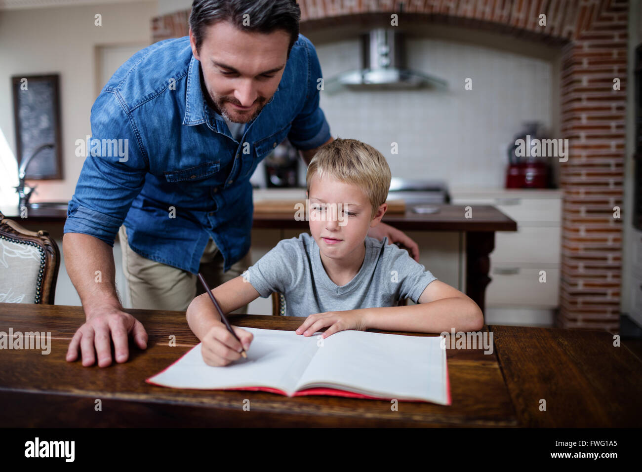Father helping son with his homework in kitchen Stock Photo - Alamy