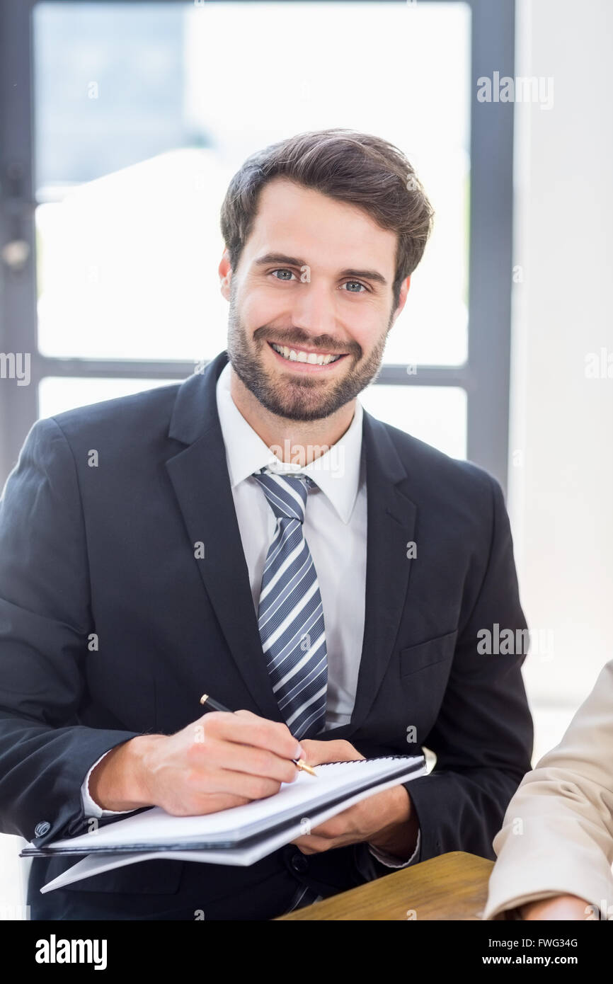 A businessman is posing, smiling and holding a pen and a book Stock ...