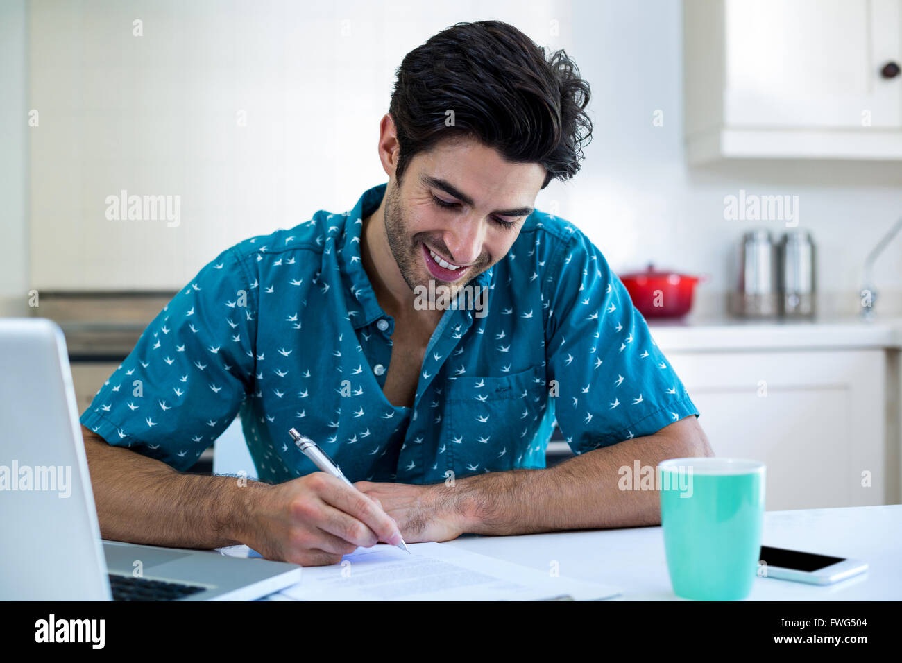 Happy man writing on clipboard in kitchen Stock Photo - Alamy