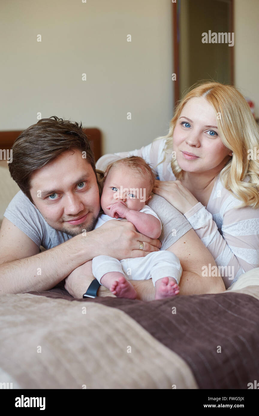 mom and dad playing with his baby son on the bed. Happy family concept ...
