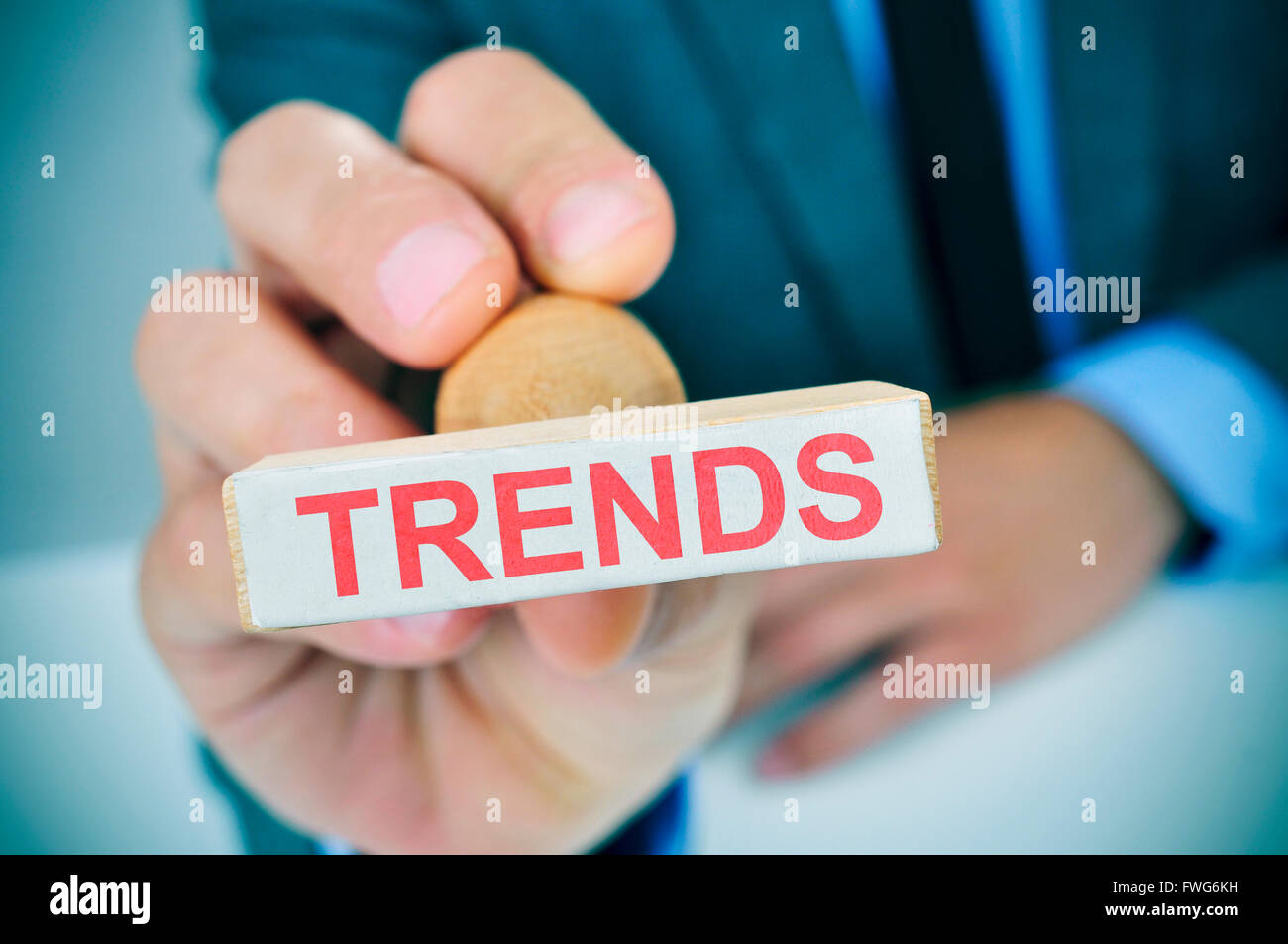 closeup of a young caucasian man at his office desk with a rubber stamp with the text trends Stock Photo