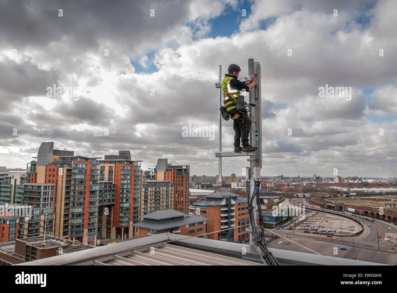 Engineer working on mobile phone aerial on an office rooftop. Antenna