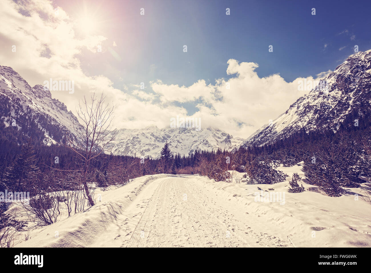 Vintage toned mountain landscape, road in Tatra Mountains against sun with lens flare,  Poland. Stock Photo
