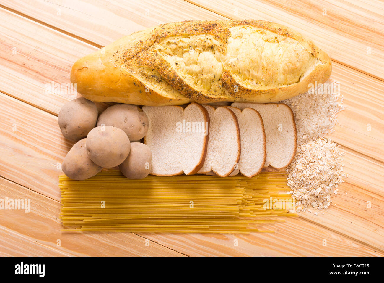 Group of carbohydrates for diet, bread, rice, oat, potatoes, pasta on wood table Stock Photo