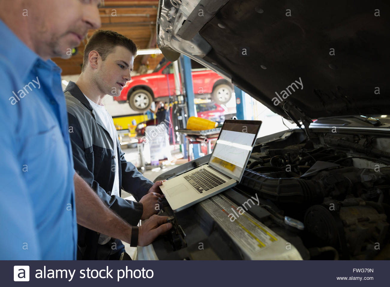 Mechanics with laptop performing engine diagnostics Stock Photo Alamy