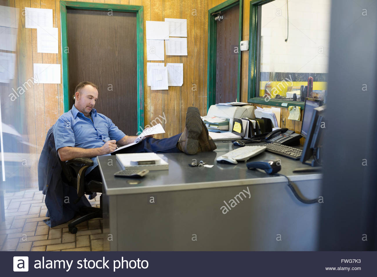 Mechanic working with feet up auto shop office Stock Photo