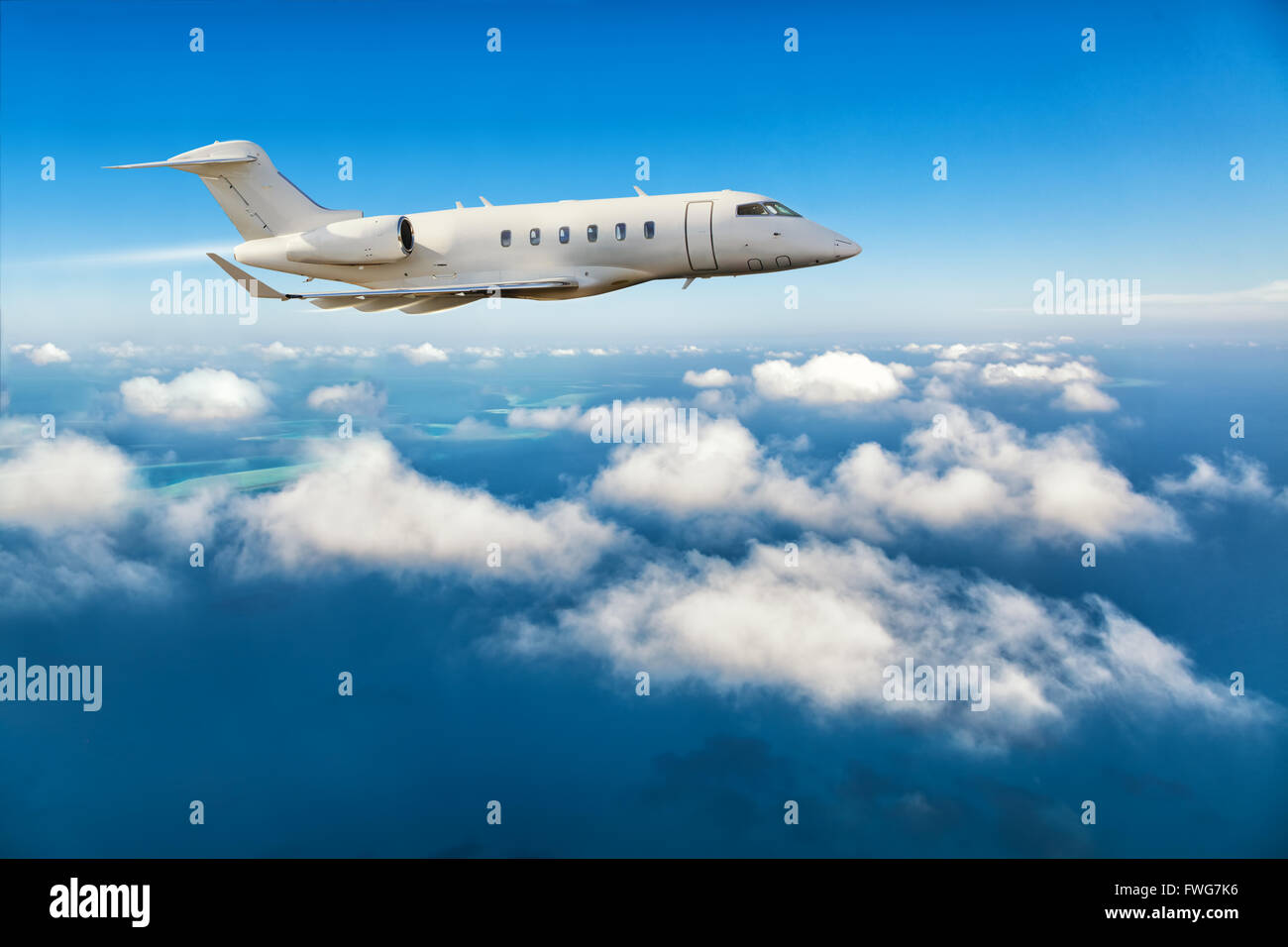 Luxury private jet plane flying above clouds in day light Stock Photo
