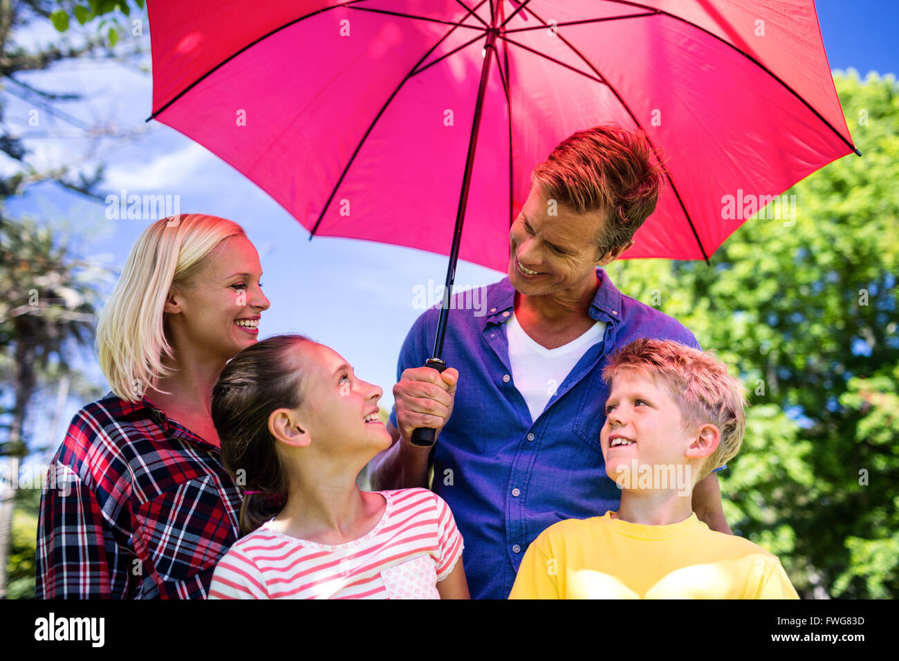 Family standing under umbrella Stock Photo Alamy