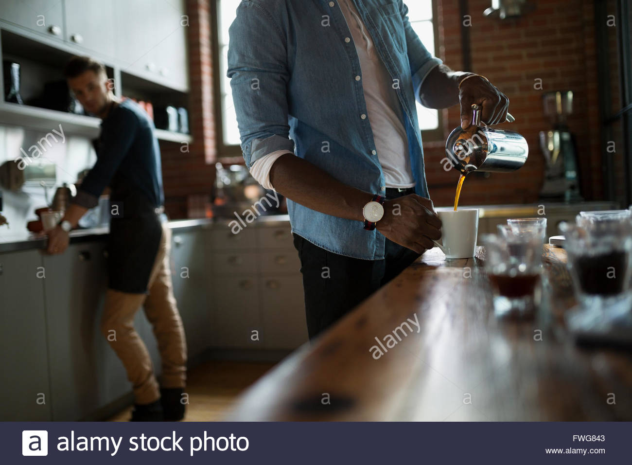 Entrepreneurial coffee roasters pouring coffee in kitchen Stock Photo