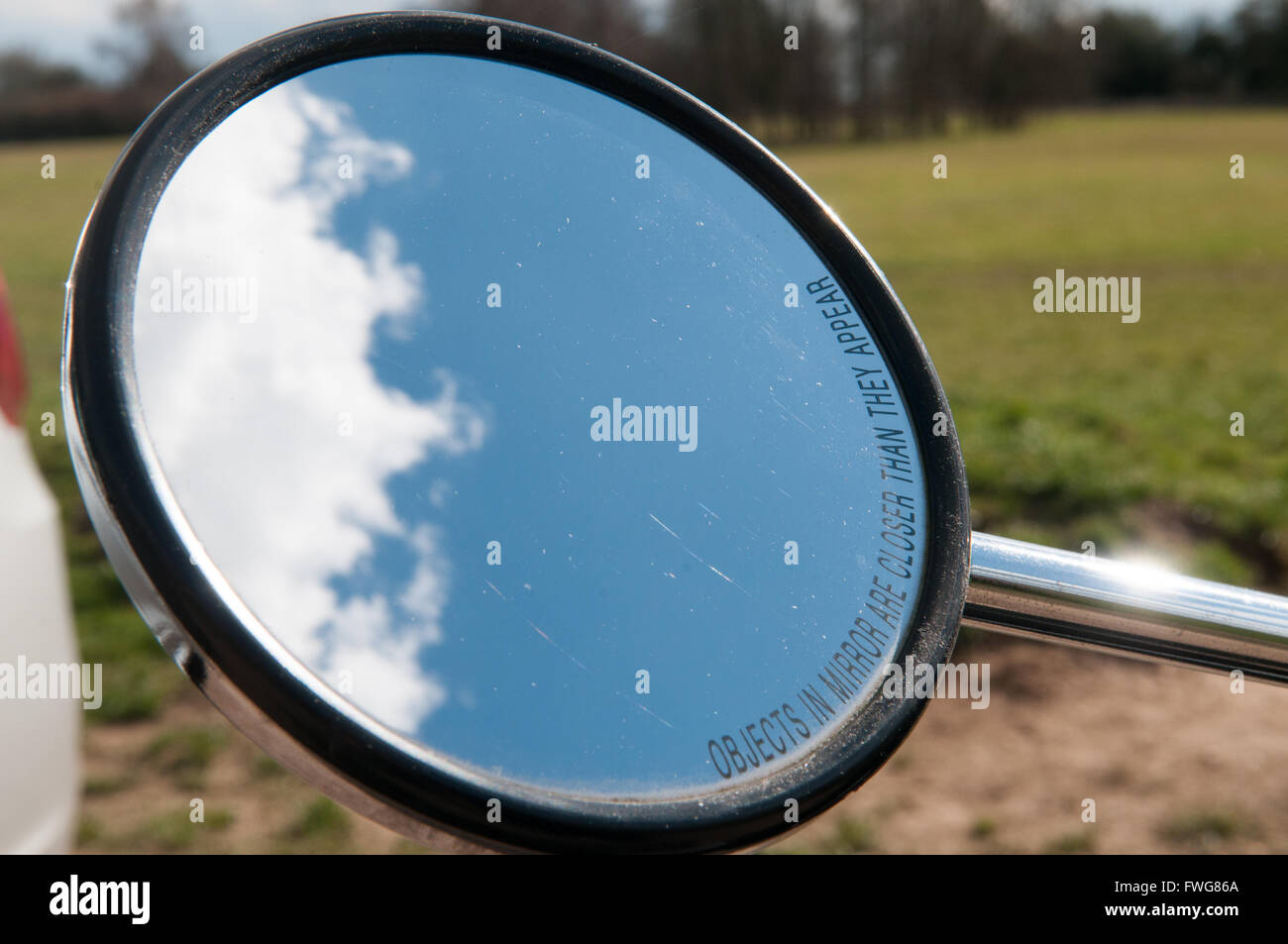 Rear view mirror of a motorcycle with clouds in view Stock Photo