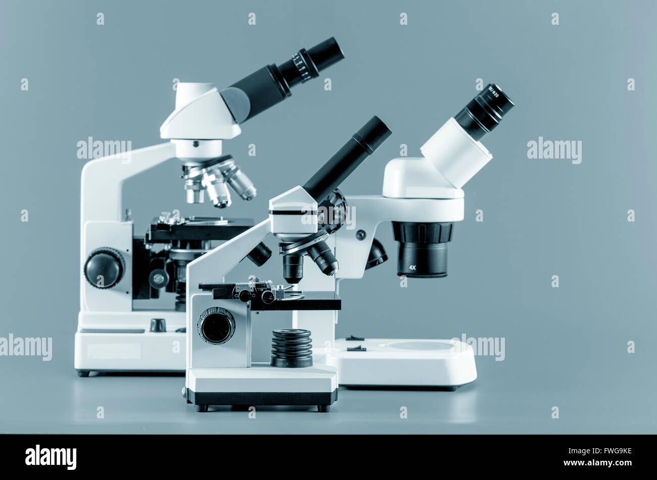 Monocular, binocular and trinocular microscopes against a grey