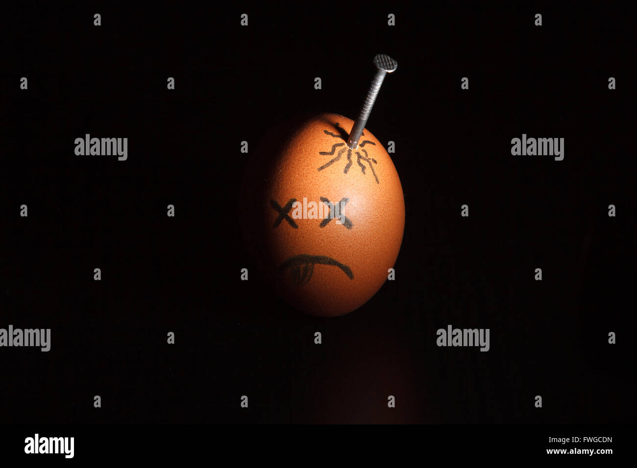 Sad egg character with nail in in the head isolated over black background Stock Photo