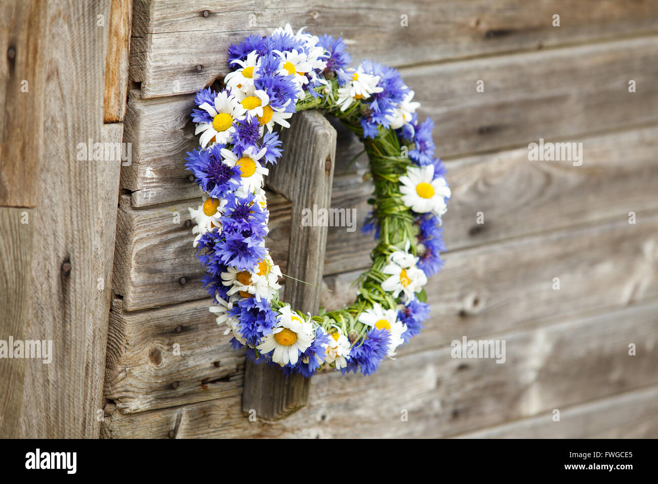 Chaplet from blue cornflowers on the wooden door Stock Photo