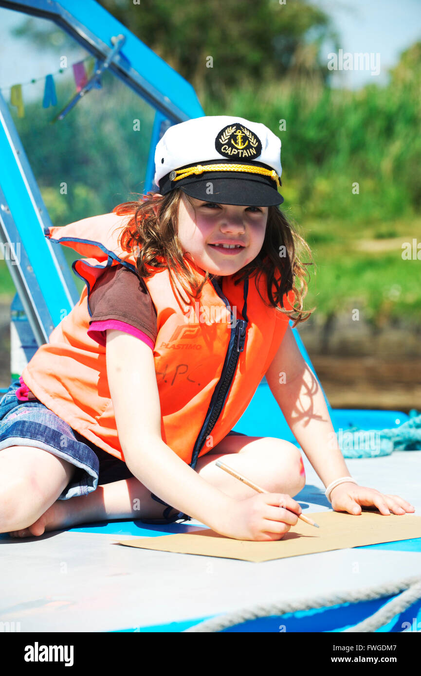 Young child wearing a life jacket is on a boat on the Norfolk Broads during Summer on the