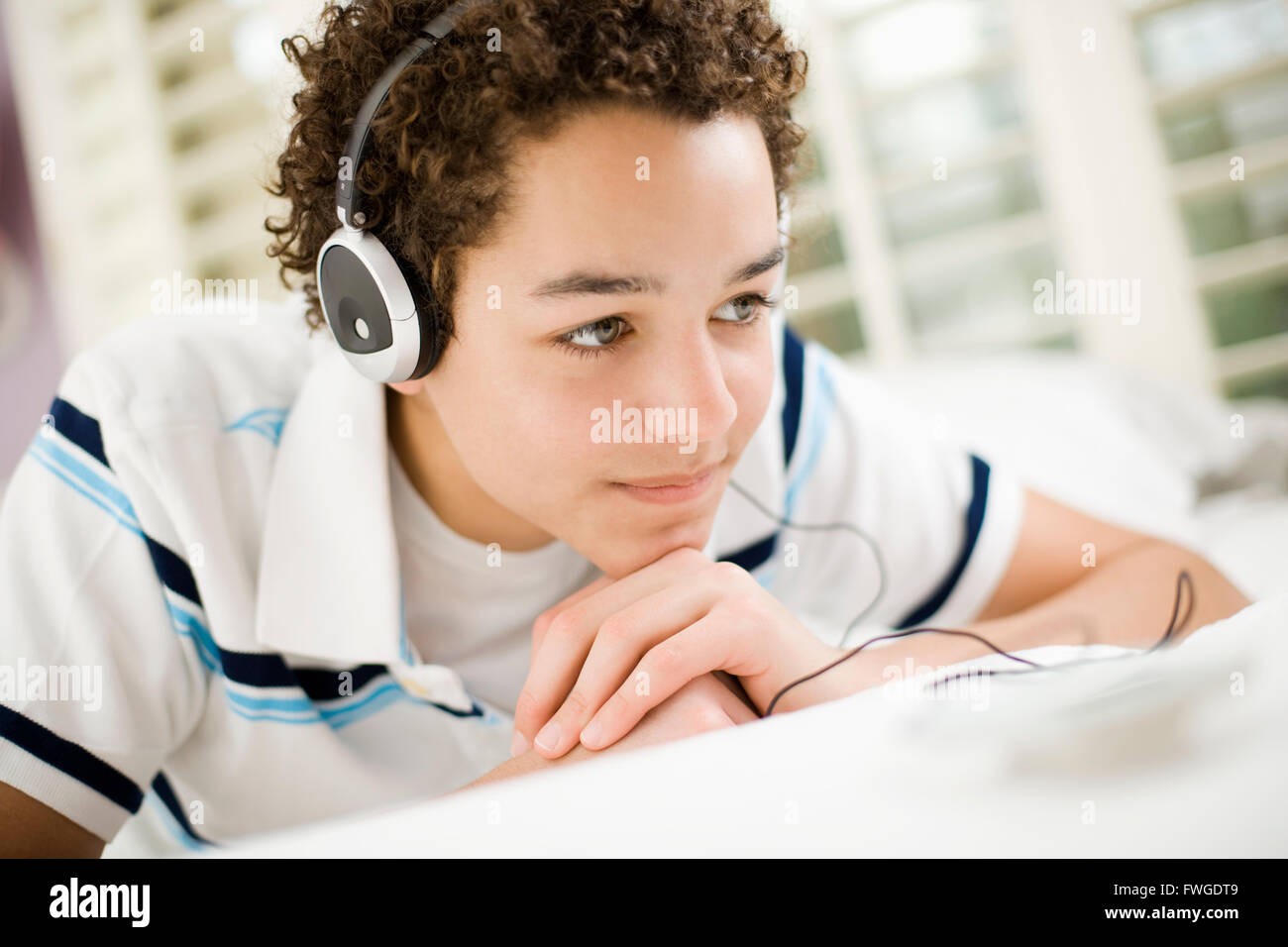 A boy wearing headphones lying on his stomach. Stock Photo
