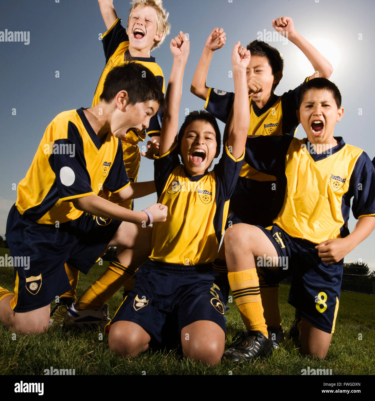 A group of boys in soccer team shirts holding a trophy and celebrating a win. Stock Photo