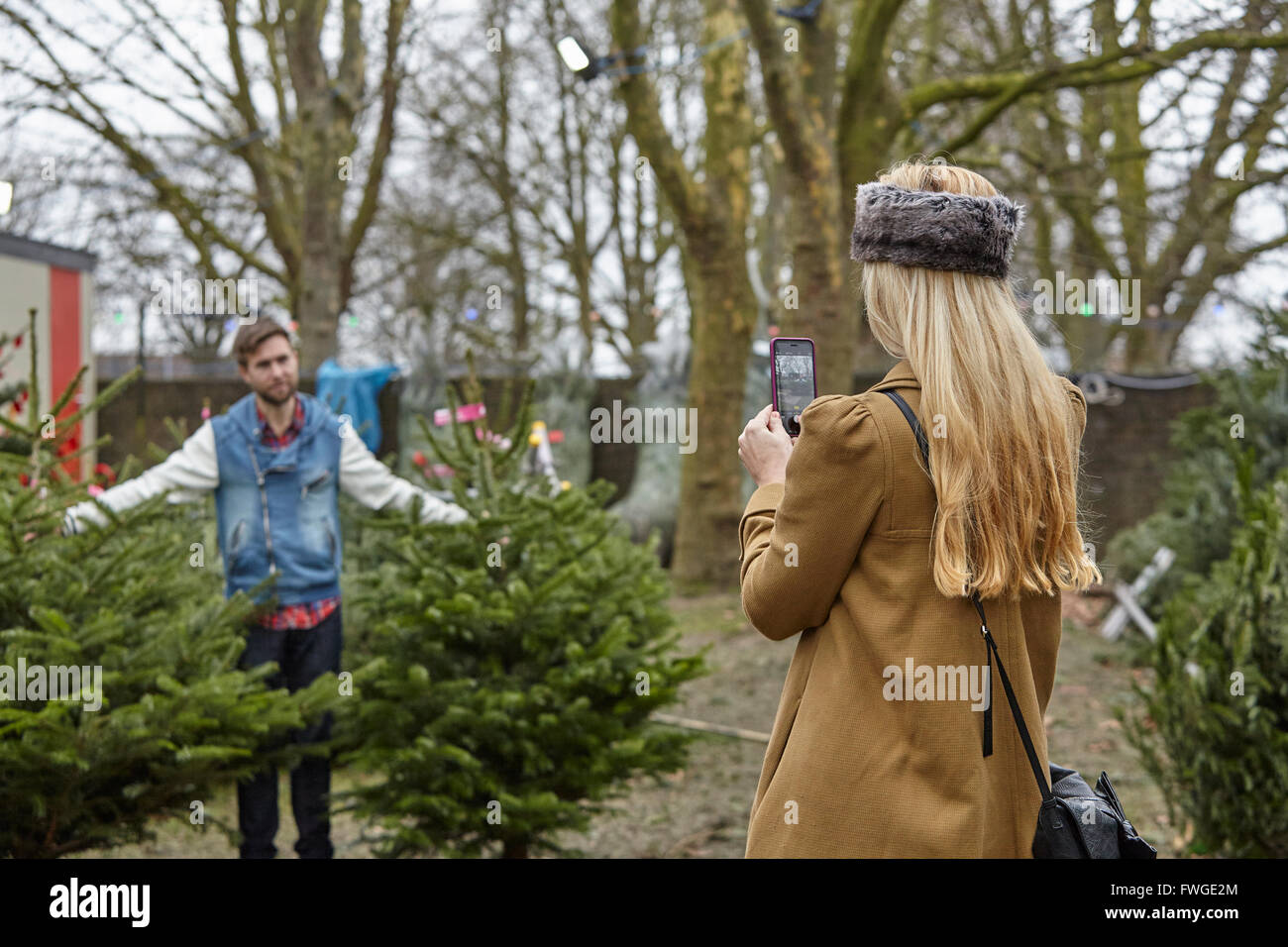 A woman shopping for a Christmas tree, assisted by staff. Stock Photo