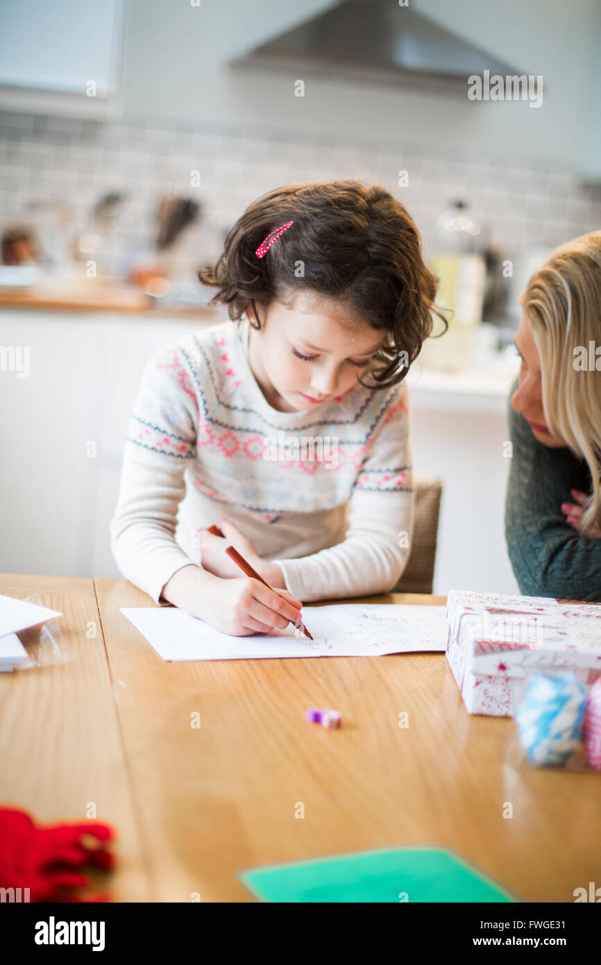 A girl at a table drawing in a card, a letter to Santa. Stock Photo