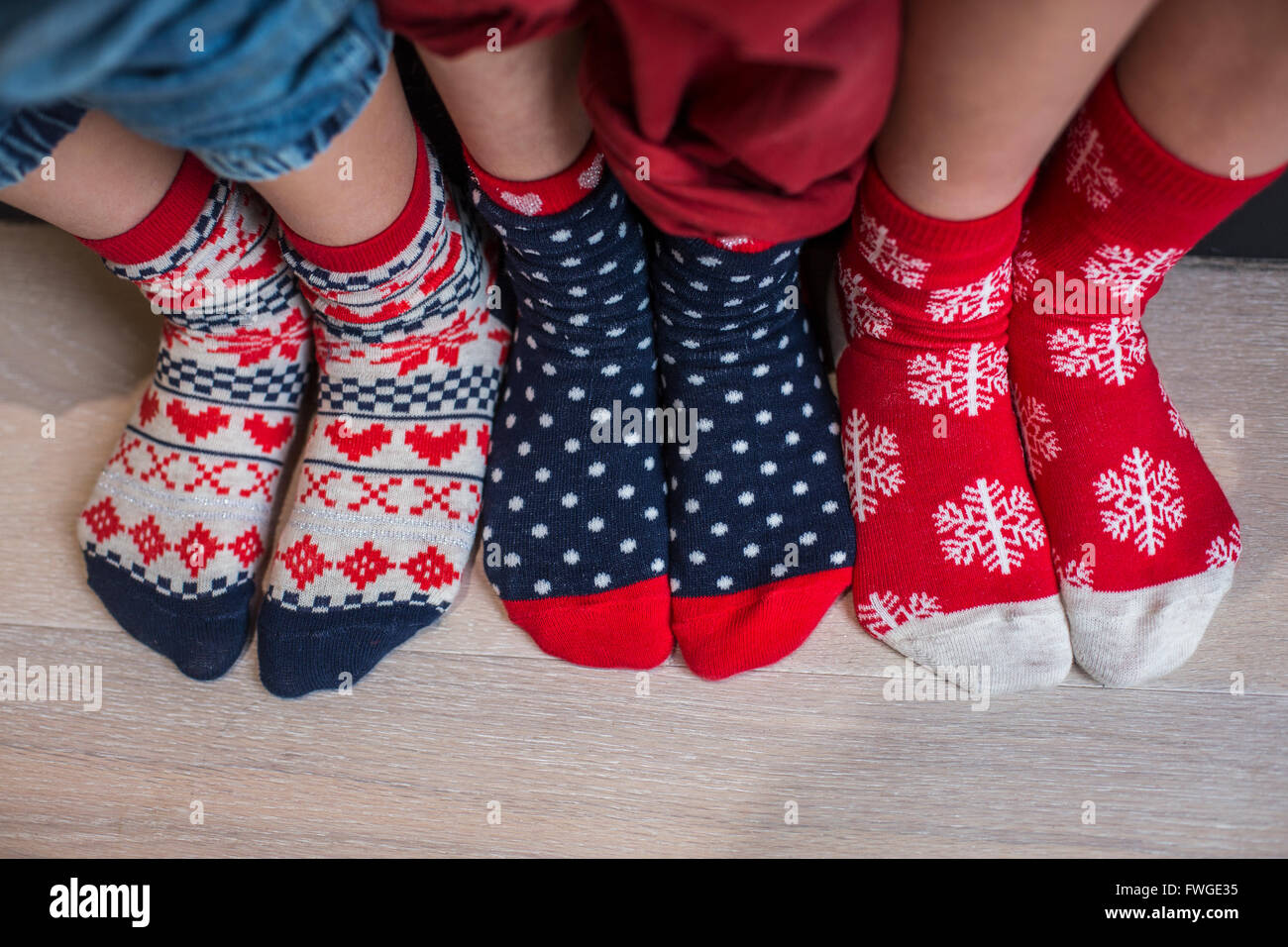 Three pairs of children's feet in bright patterned Christmas socks. Stock Photo