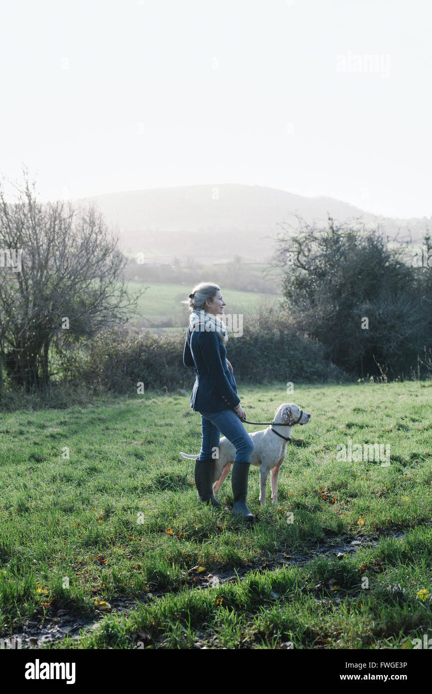 A woman walking with a dog on high ground overlooking the countryside. Stock Photo