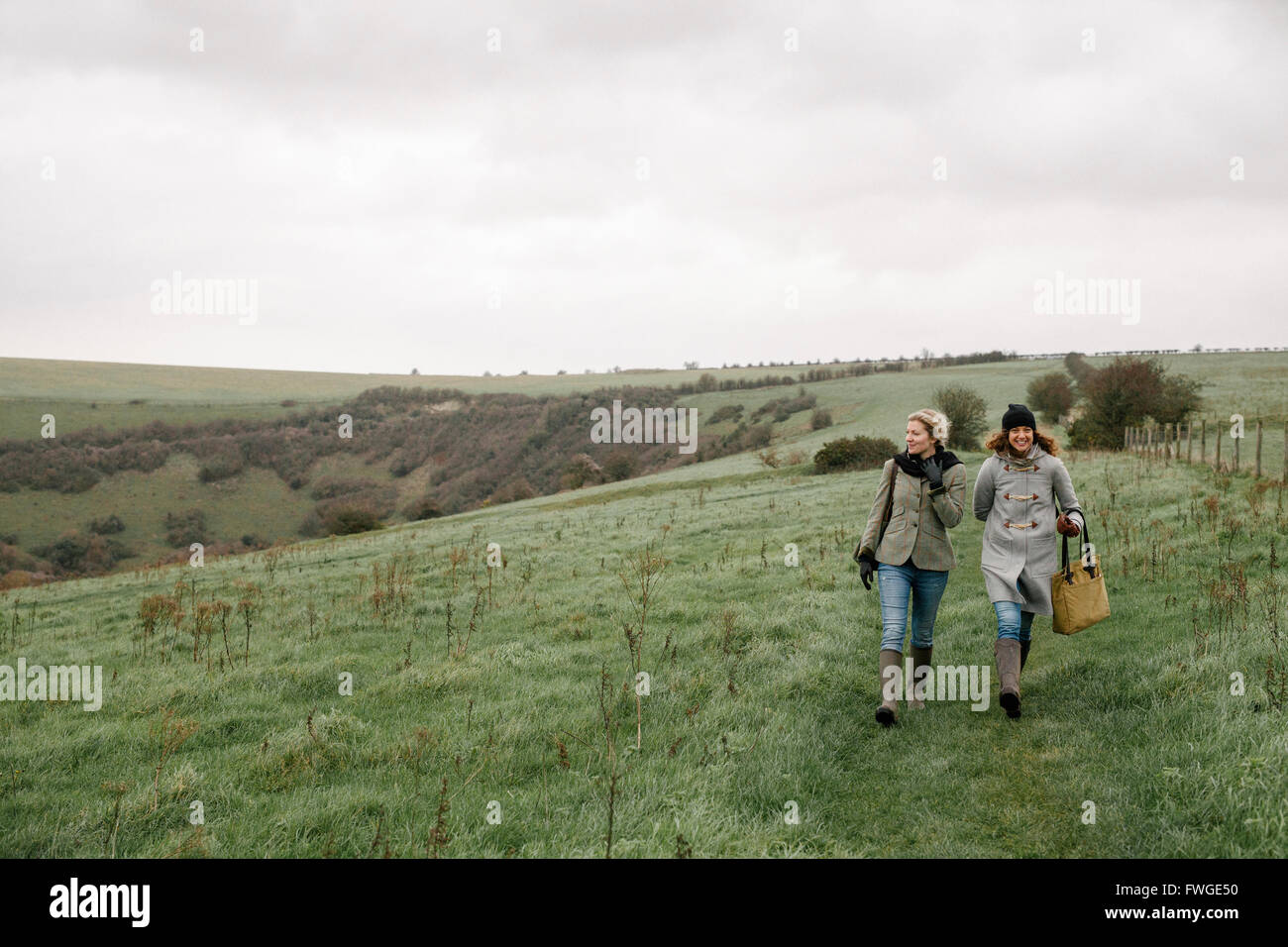 Two women walking on a country path across grassland. Stock Photo