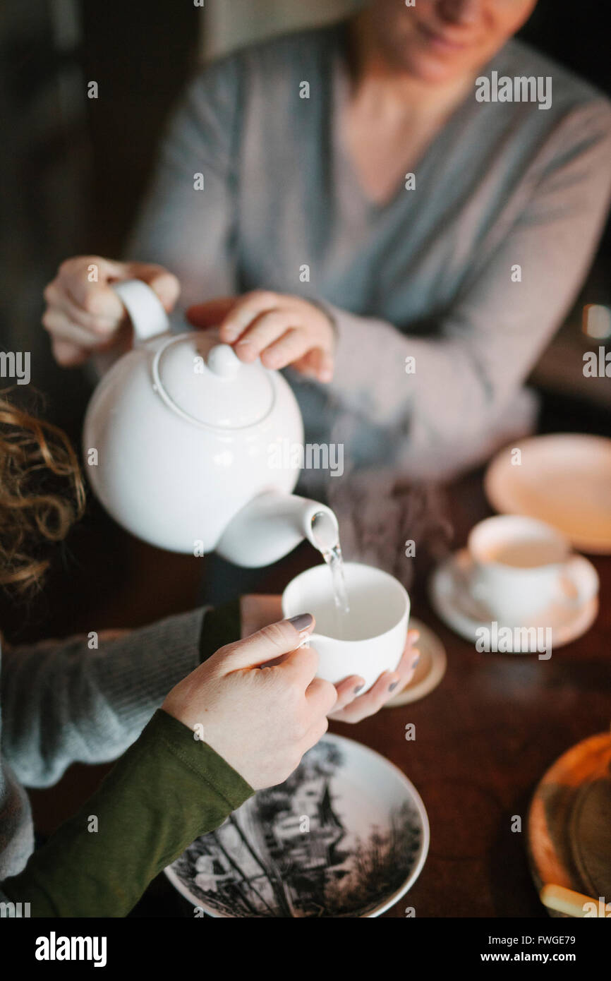 https://c8.alamy.com/comp/FWGE79/a-woman-pouring-tea-from-a-teapot-into-a-cup-for-a-companion-FWGE79.jpg