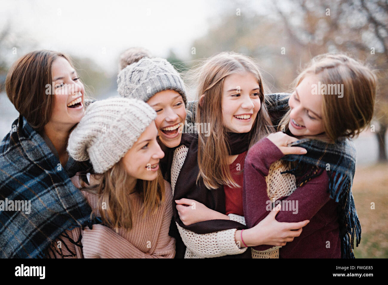 Five young people, girls, friends in warm shawls and woolly hats outdoors. Stock Photo