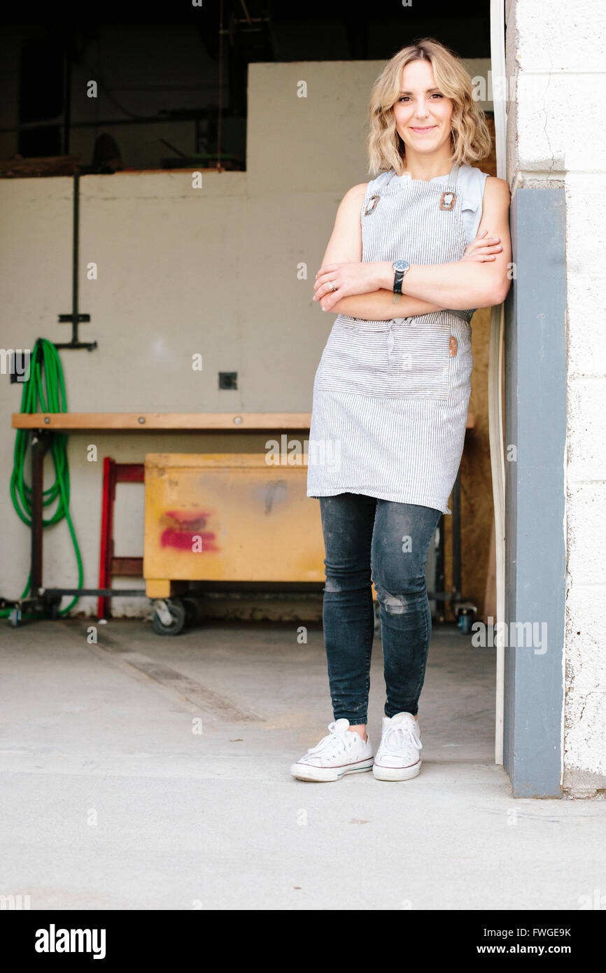 A business owner and craftsman standing in the doorway of her workshop. Stock Photo