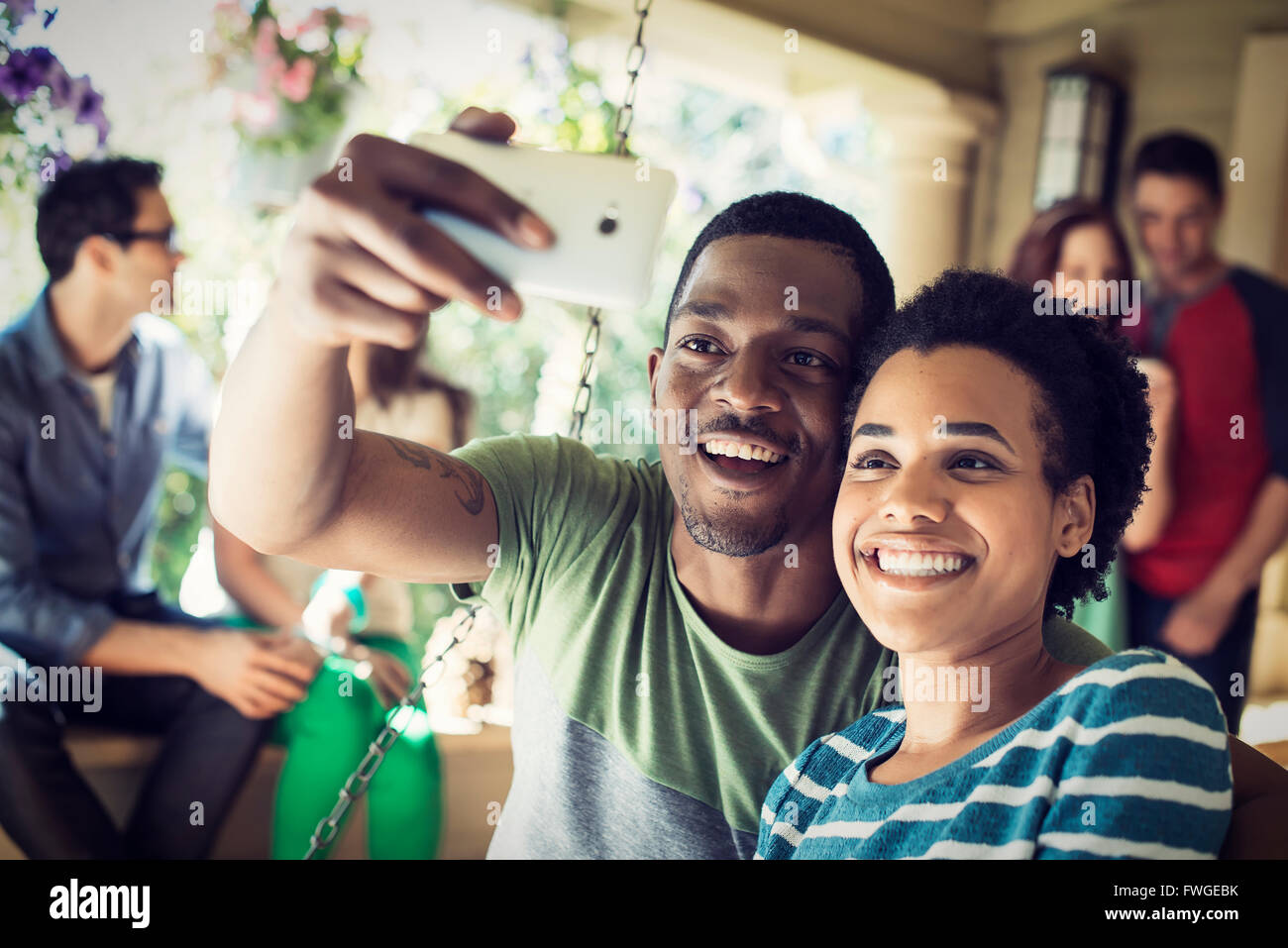 A group of friends, men and women at a house party. A couple taking a selfie. Stock Photo
