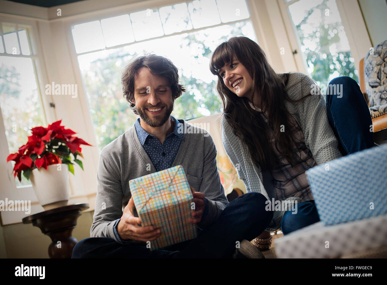 A couple on a sofa, exchanging wrapped presents. Stock Photo