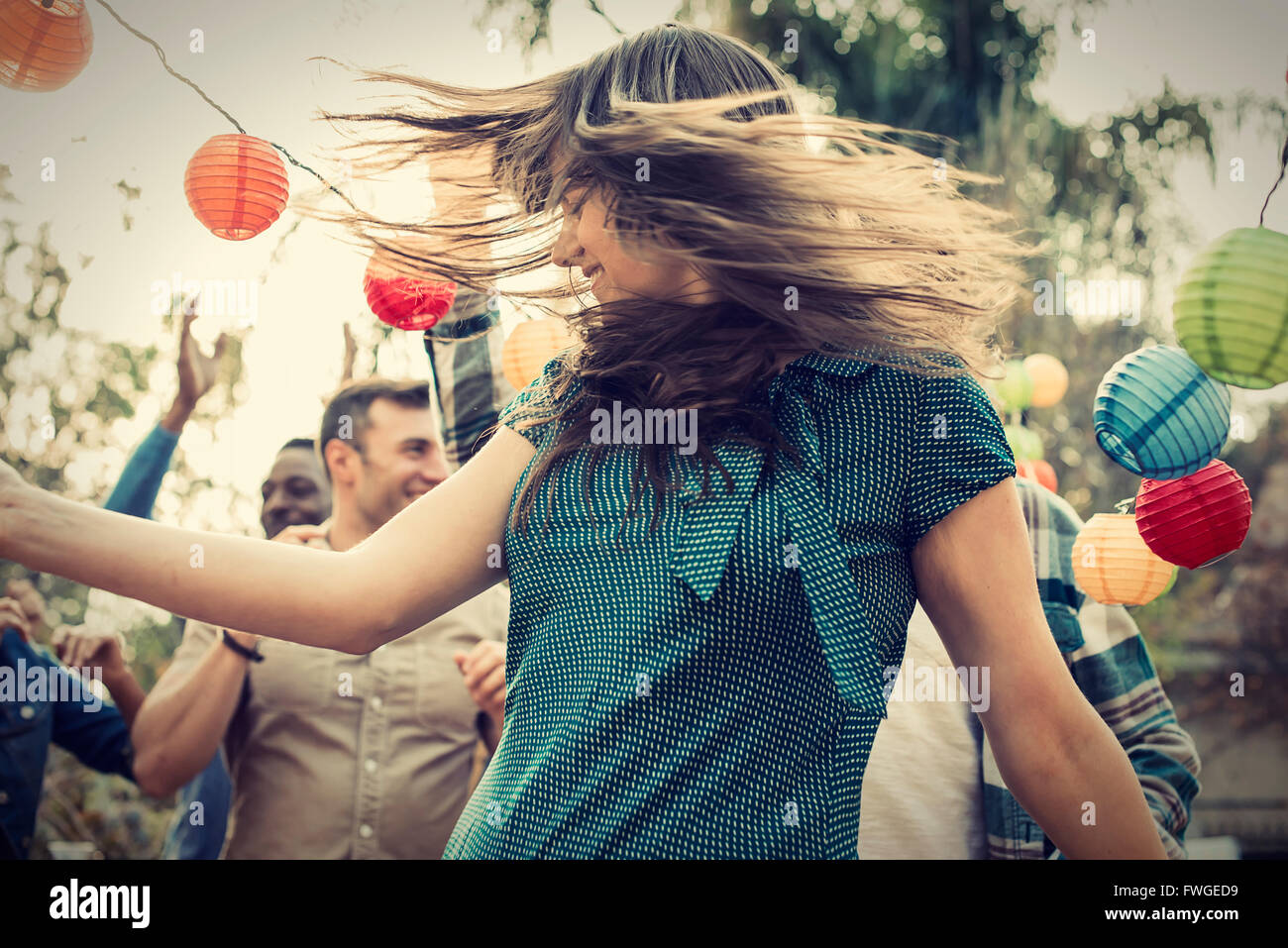 A group of men and women at a party dancing outdoors. Stock Photo
