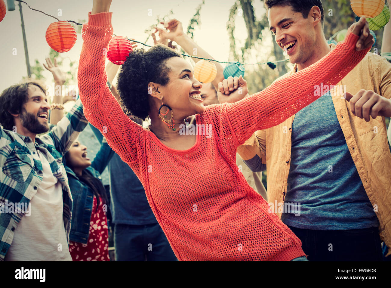 A group of men and women at a party dancing outdoors. Stock Photo