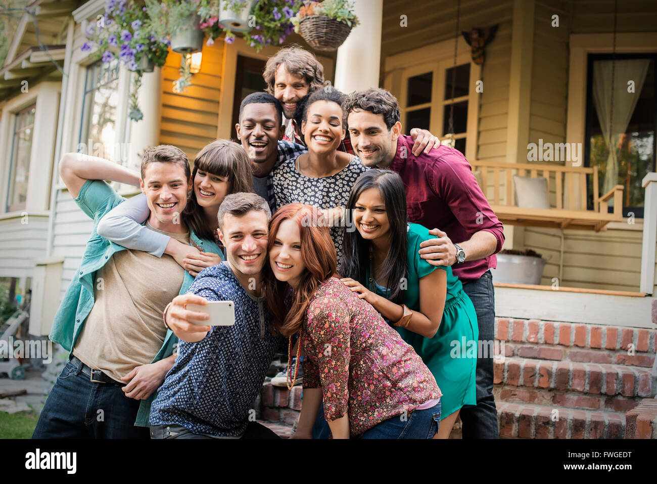 A group of friends posing on the steps of a house porch, taking a group selfy. Stock Photo