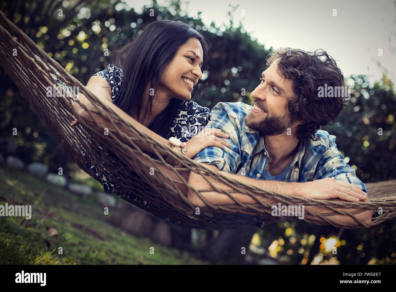 A couple, a young man and woman lying in a large hammock in the garden. Stock Photo