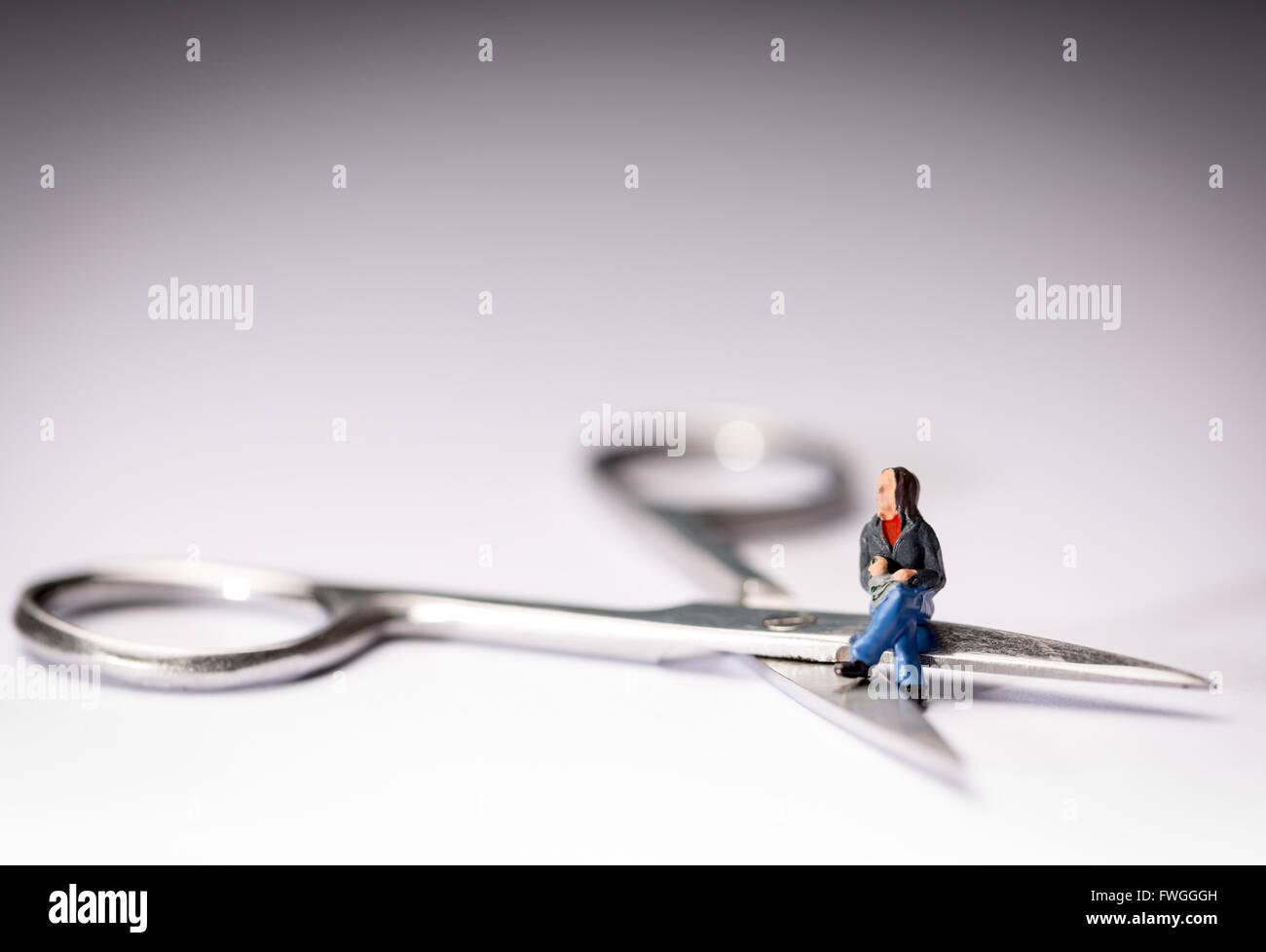 Vasectomy concept image of a miniature figure sat cross legged on a pair of scissors Stock Photo