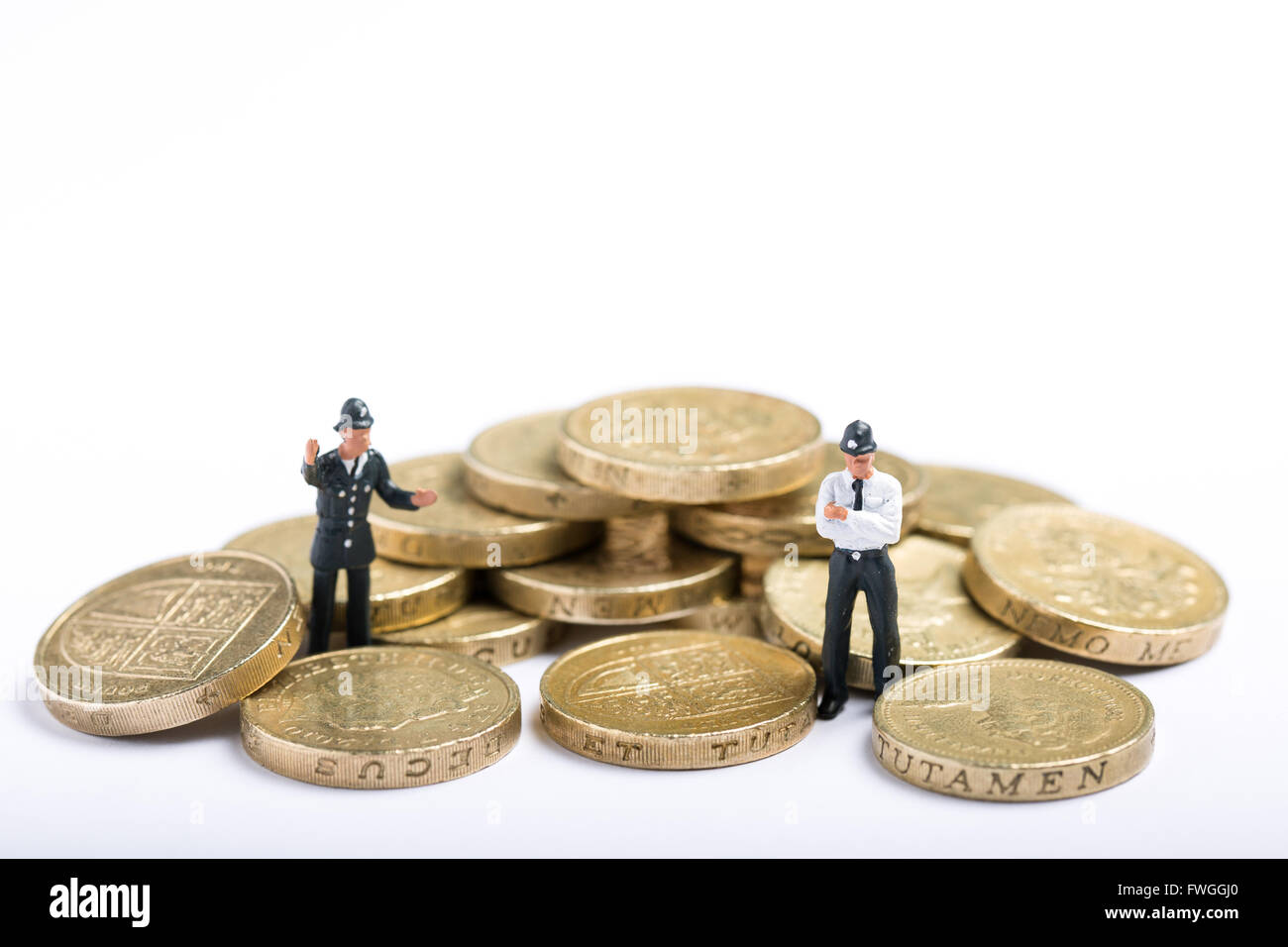 Miniature police figures stood with a pile of pound coins. There are nearly 45 million fake pound coins in the UK Stock Photo